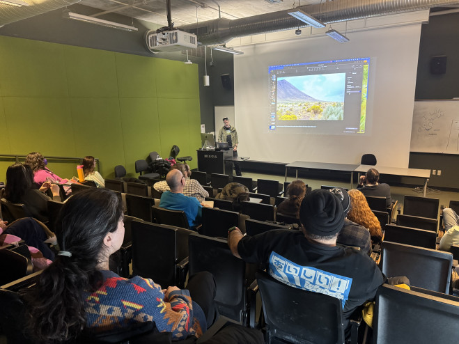 Faculty member presenting in Brown 320 with projected image while students are seated in the foreground of the photo