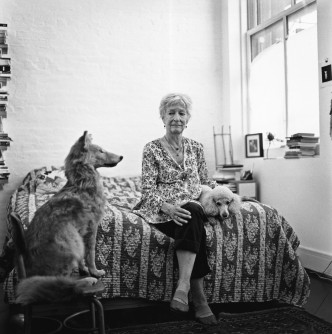 Joan Jonas seated on a bed with two dogs