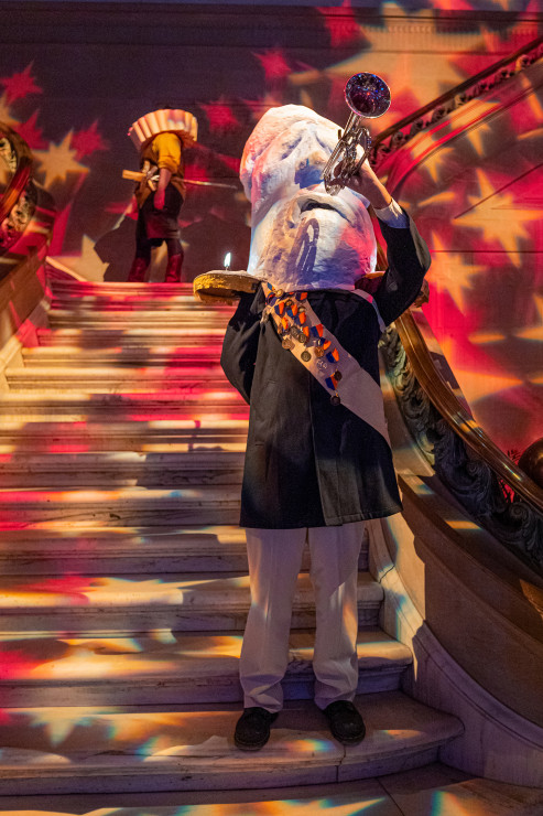 At the Fête of Lights: Bicentennial Gala, Aidan Leizerov ’28 (Interdisciplinary Sculpture BFA) wore their wax soldier costume created in the Mask and Headdress course taught by Valeska Populoh, faculty in the Fiber, Fashion, and Textile program. On the upper landing, Martin Knuppel ’26 (Illustration and Printmaking BFA) is dressed as a modern version of the First Lord of Baltimore. Leizerov and Knuppel were part of a larger student interpretation of the Main Building’s Maryland painting. Students created a living mural that was more representative of MICA's students today.